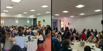 Partecipanti seduti in gruppi intorno a tavoli rotondi durante un workshop o evento formativo in una sala conferenze. L’atmosfera è collaborativa e professionale.