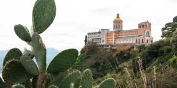 Basilica Santuario Maria del Tindari sulla collina con piante di fico d’India in primo piano.