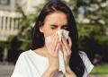 Donna che starnutisce con un fazzoletto all’aperto, sintomi di allergia ai pollini