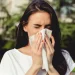 Donna che starnutisce con un fazzoletto all’aperto, sintomi di allergia ai pollini